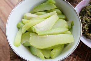 Boiled herbs and vegetables in white bowl on Kantoke, Kind of wooden utensil in northern of Thailand for put the foods to serve photo