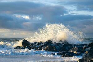 Wave crashing at rocks at danish coast photo