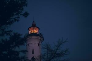 Lighthouse in the early morning hours through some branches photo