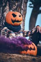 Person with pumpkin head sitting in smoke photo