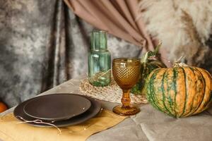 Autumn interior. a table covered with dishes, pumpkins, chair, casual arrangement of Japanese pampas grass. Interior in the photo Studio.