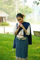 Portrait of Beautiful rural Thai woman wear Thai northern traditional dress acting for photo shoot in public park