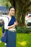 Portrait of Beautiful rural Thai woman wear Thai northern traditional dress acting for photo shoot in public park