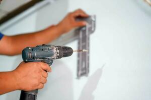 Closeup hands of builder holding an electric drill is drilling a hole in the wall for install air condition at construction site. photo