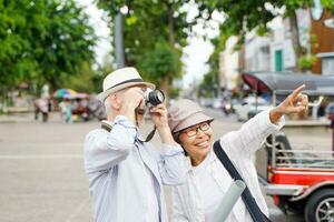 Closeup American senior tourist man take a photo in the city with his tour guide on blurred background. Senior tourist concept