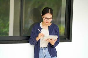 Closeup Asian young female student in casual cloth reading classroom lecture from tablet for the exam photo