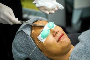 Closeup Asian beauty woman receiving skin gel to prepare the color light therapy to stimulate facial health. photo