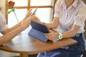 Closeup and crop hands of Student doing homework on tablet and smart phone at school with sun flare background. Network education concept. photo