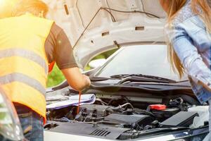 Closeup and crop motor vehicle mechanic checking engine oil to record the repair history with sun and lens flare background. photo