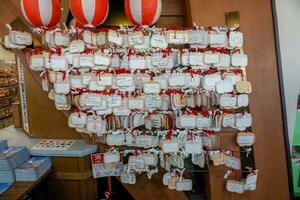 Osaka City, Japan, 2019 - Wishing Wooden tag in baby feet's shape with blessing texts from people and tourist hang on wooden wall of Billiken shrine. photo