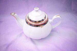 Old-fashioned porcelain tea pot with fabric background photo