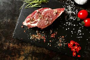 raw pork with spices for cooking on a fire or oven on a dark stone background photo