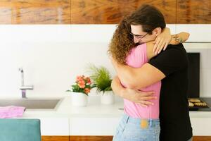 Happy couple standing in kitchen and hugging each other in daylight photo