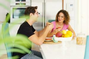 contento adulto Pareja sentado a comida mesa y hablando durante desayuno a hogar foto