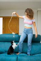 Woman playing with cute cat on sofa photo