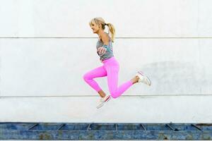 Happy active woman jumping above ground on street photo