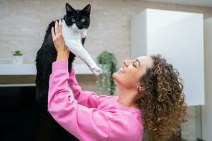 Happy young woman spending time playing with cute cat photo