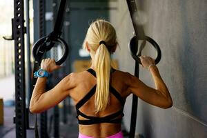 Unrecognizable female doing exercises with fitness gymnastic rings in modern gym photo