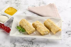 Homemade stuffed pancakes with honey and cream sour photo
