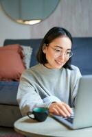 retrato de trabajando mujer de negocios utilizando computadora portátil, trabajo en remoto. coreano niña con computadora, tiendas en línea foto