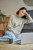 vertical Disparo de hermosa asiático mujer, estudiante sentado a hogar y estudiando de forma remota, elearning con ordenador portátil foto