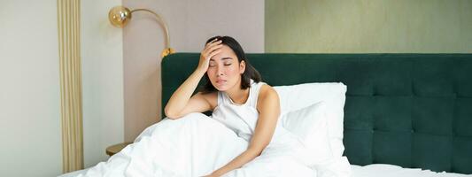 Portrait of sad young woman waking up, feeling bad, wants to sleep, wakes early morning, looking lazy and upset photo