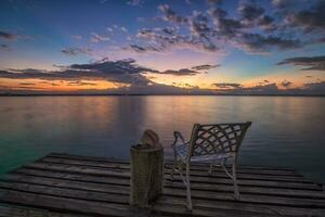 vacío silla en un de madera muelle esperando para amanecer en el mar playa. foto