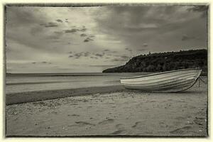 Black and white seascape of a wooden boat on the beach. Vintage view photo