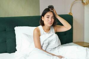 retrato de triste joven mujer despertar arriba, sensación malo, quiere a dormir, despierta temprano mañana, mirando perezoso y trastornado foto