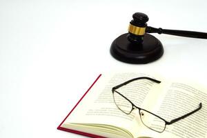 Close up judge gavel or hammer placed behind and blurred glasses with law book. Law, judiciary concept. photo