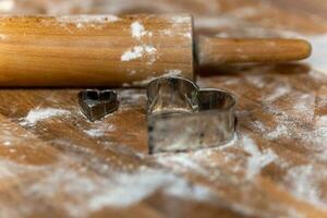 a rolling pin with flour and cookie molds photo