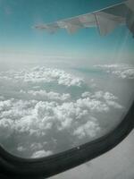 sky and clouds from airplane wing as seen through window of an aircraft photo