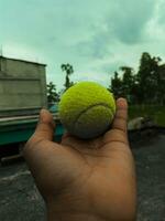 cerca arriba Disparo de tenis pelota desde el mano. cinematográfico foto