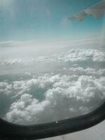 sky and clouds from airplane wing as seen through window of an aircraft photo