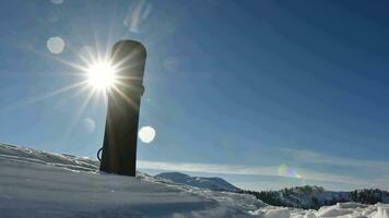 Static time-lapse snowboard in snow on skiing slope with clear blue sky and sunburst banner copy space background video