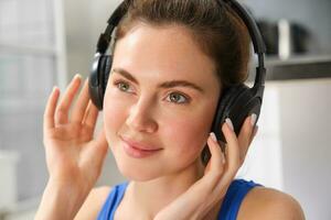 Face of beautiful woman in wireless headphones, enjoys sound, listens to music in wireless headphones photo