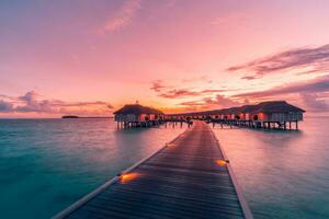 increíble panorama de la puesta de sol en maldivas. Villas de resort de lujo marino con luces LED suaves bajo un cielo de colores. hermoso cielo crepuscular y nubes de colores. hermoso fondo de playa para vacaciones vacaciones foto
