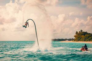 Maldives island sunset. Professional fly board rider doing back flip with tropical resort island background. Sunset sport and summer activity background, fun water sport 08.17.21 - Noonu atoll photo