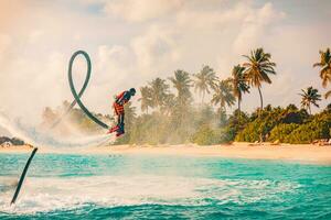 Maldives island sunset. Professional fly board rider doing back flip with tropical resort island background. Sunset sport and summer activity background, fun water sport 08.17.21 - Noonu atoll photo