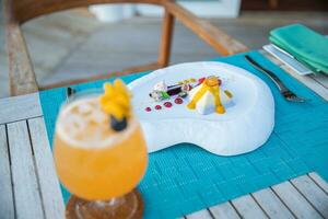 Gourmet dessert ice cream and cake with fruits on elegant close-up view. Plate with different sweet desserts and cocktails on colorful table photo