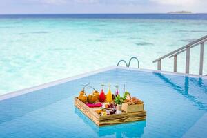 Breakfast in swimming pool, floating breakfast in tropical resort. Table relaxing in calm pool water, healthy breakfast and fruit plate by resort pool. Exotic summer diet luxury island beach lifestyle photo