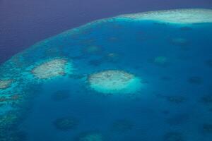 Aerial view on Maldives island atolls. Tropical islands lagoon in Maldives from aerial photography Summer exotic vacation holiday landscape background. Seaplane flying above travel landscape photo