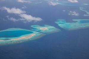 Aerial view on Maldives island atolls. Tropical islands lagoon in Maldives from aerial photography Summer exotic vacation holiday landscape background. Seaplane flying above travel landscape photo