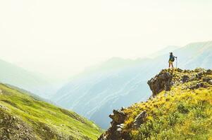 Back view fit sporty female hiker with nordic walk sticks stand on viewpoint uphill in green hiking trail in caucasus mountains .Recreational activities and healthy lifestyle photo