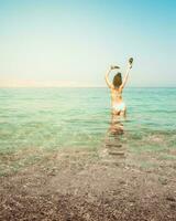 Tourist woman stand in clear turquoise water in persian gulf Mirellas island sandy white beach. Oman coastline paradise. Musandam. photo