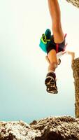 Low view female body step feet in air on hiking over rocks outdoors alone in hot sunny day outdoors. Motion blur filter. Shoe grip and footwear on climbing concept photo