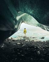Tourist woman stand by beautiful Fjallsjokull glacier in Iceland in overcast day. Ice caves in Iceland. View from small gap cave. Textures close up glacier photo