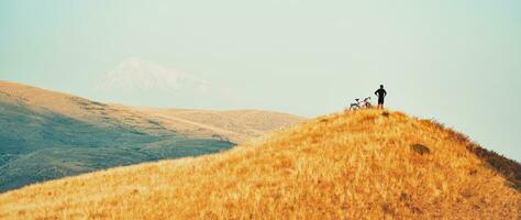 Top view fit young caucasian cyclist on top viewpoint enjoy inspirational mountains background in armenian caucasus. Achievement , inspiration, challenge and determination concept photo