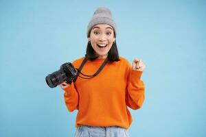 Passionate asian girl photographer, taking pictures on her digital camera, capturing moments outdoors, shooting photos, blue background photo