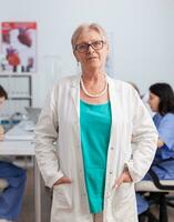 Portrait of senior pediatrician woman standing in front of camera working in conference meeting room. Cardiologist doctor with stethoscope presenting medical expertise analyzing sickness treatment photo